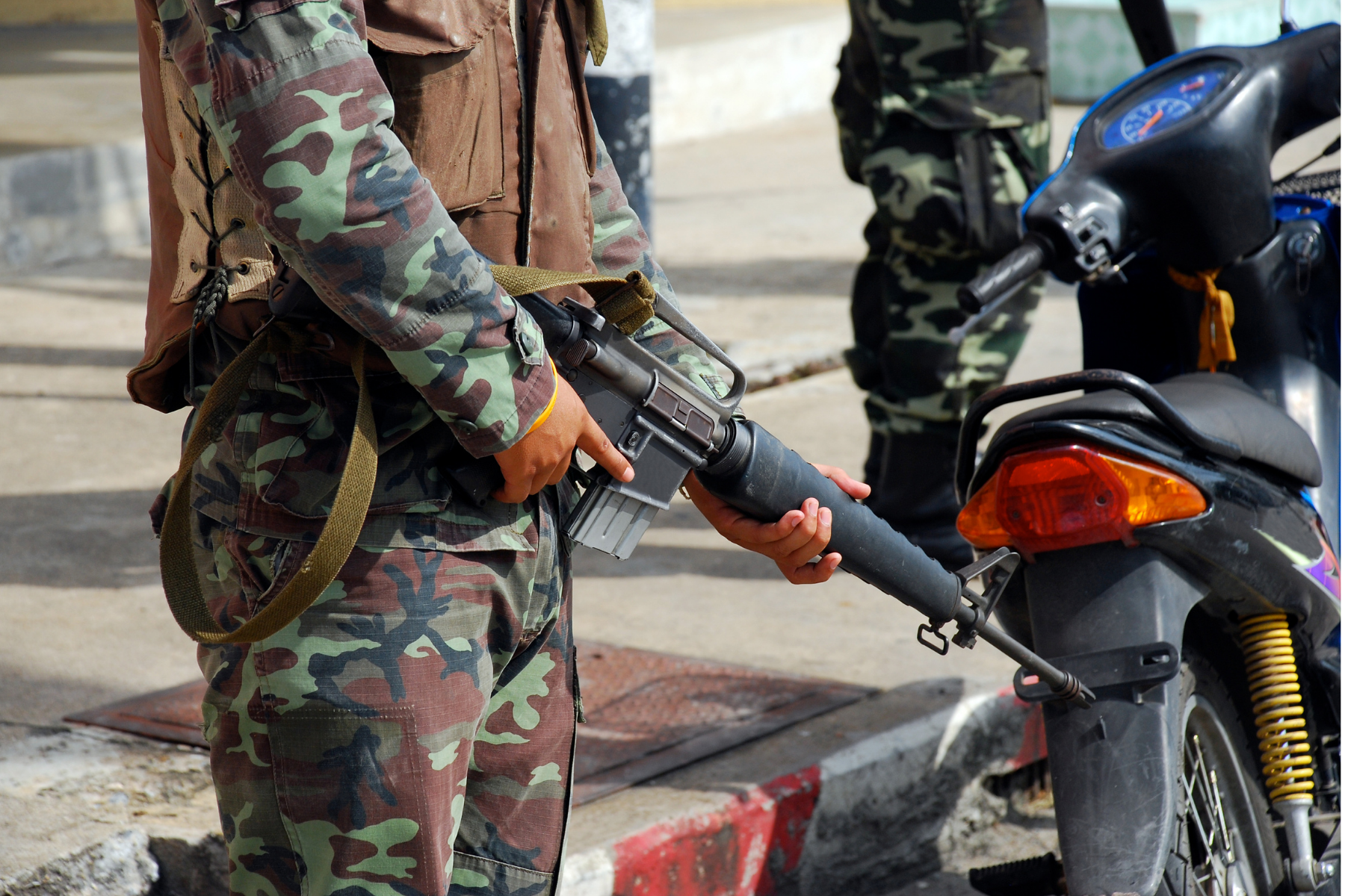 Person in camouflage holding an automatic gun.