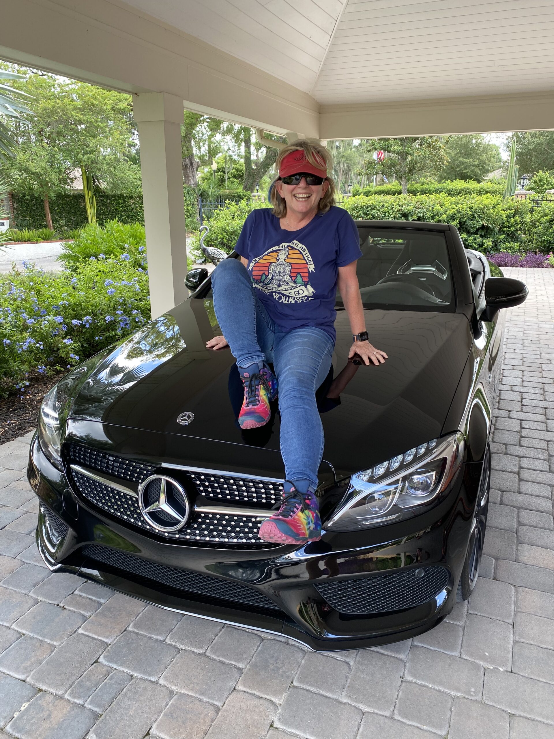 Honey Rand sitting on the hood of her Mercedes convertible.