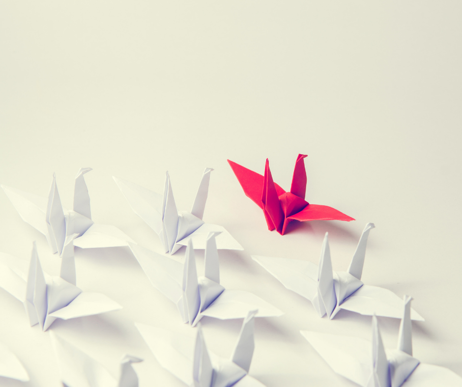 Rows of white origami birds with one red bird.