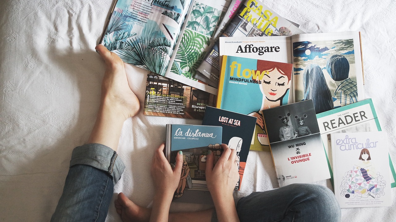 Magazines and books spread across a bed.